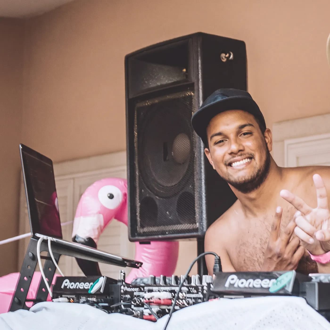 O Yuri a sorrir atrás do setup de DJ, em casa, com um flamingo insuflável